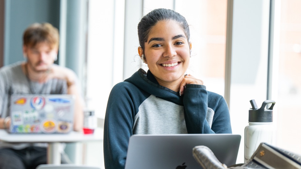student smiling at camera with laptop